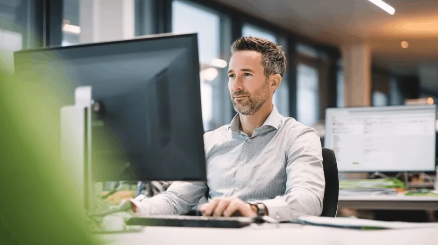 Pracownik przy monitorze w biurze – enova365 Document Management System