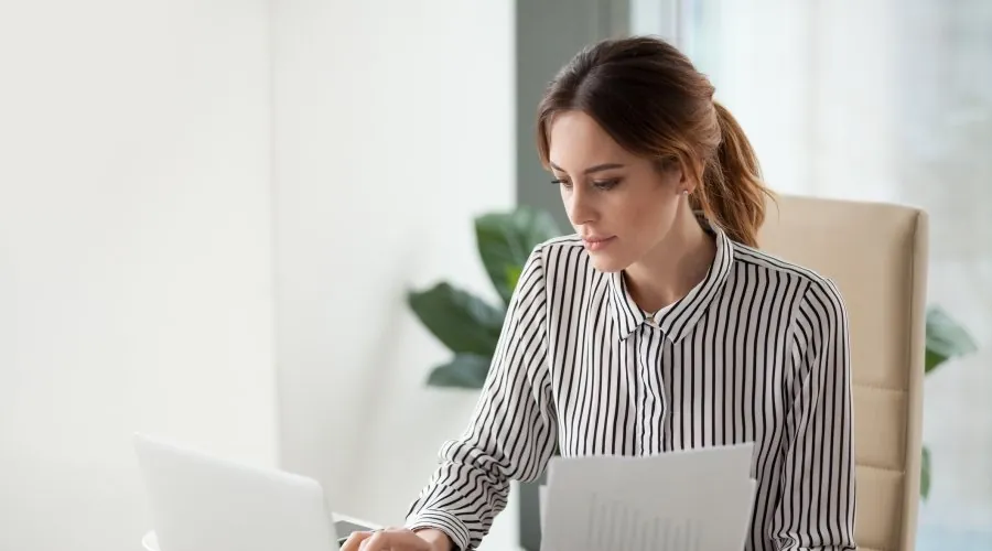 Pracowniczka z dokumentami przy laptopie – enova365 Faktury