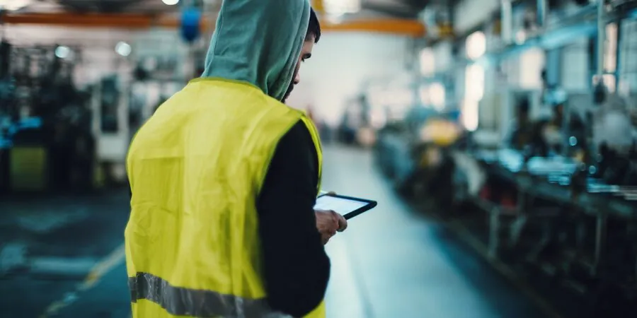 Pracownik produkcji z tabletem przy linii – Panel Meldunkowy enova365